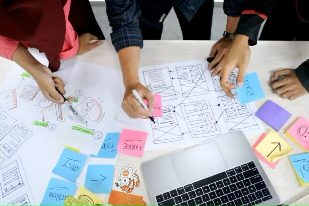 People working at a table covered in post-it notes and images 